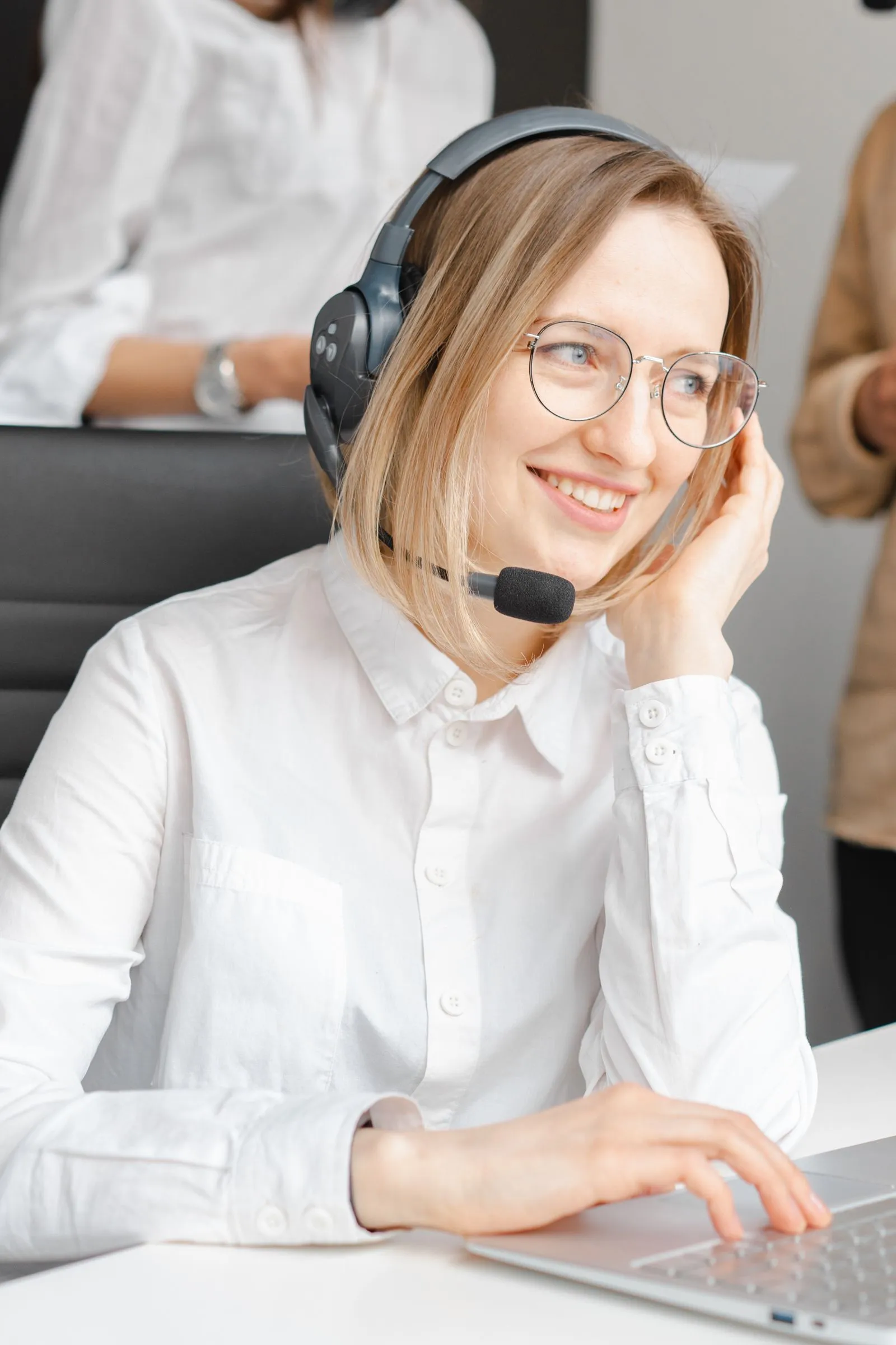 A smiling support agent wearing a headset at her desk